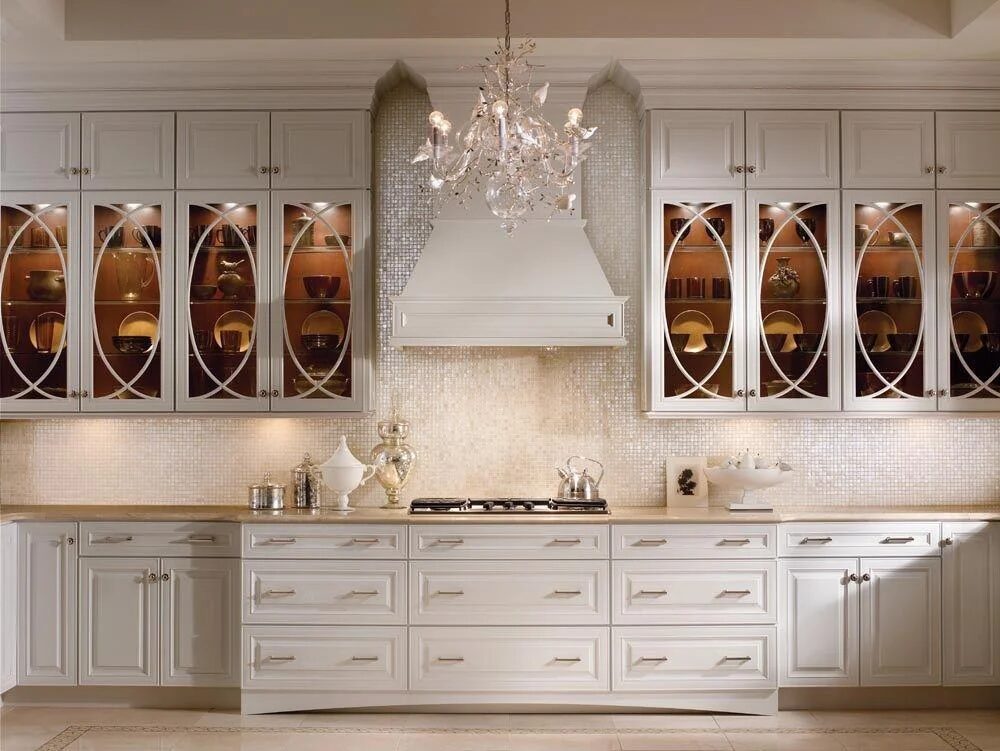 Ornate white kitchen with arched glass cabinet doors and chandelier