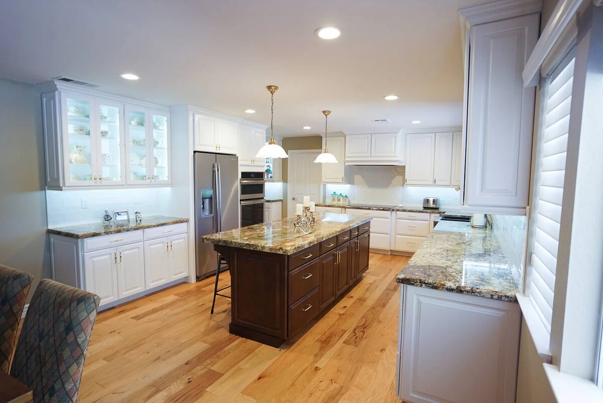 White kitchen with granite island and hardwood flooring