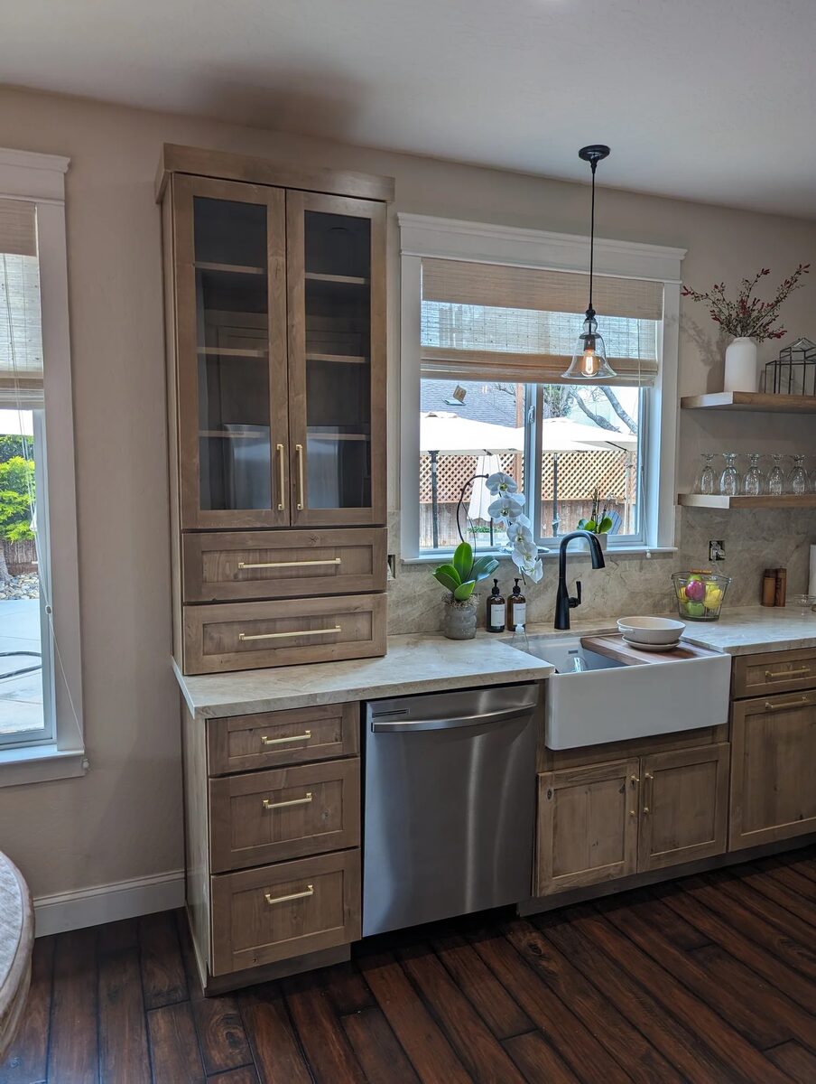 Light wood kitchen with farmhouse sink and glass upper cabinets